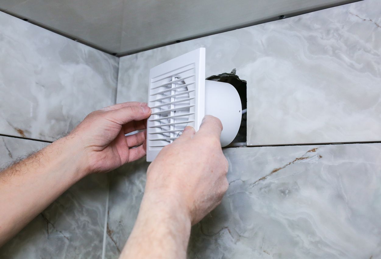 Man is installing the wall bathroom fan vent. Restoration process. nettoyage VMC pour diminuer la condensation dans la salle de bain