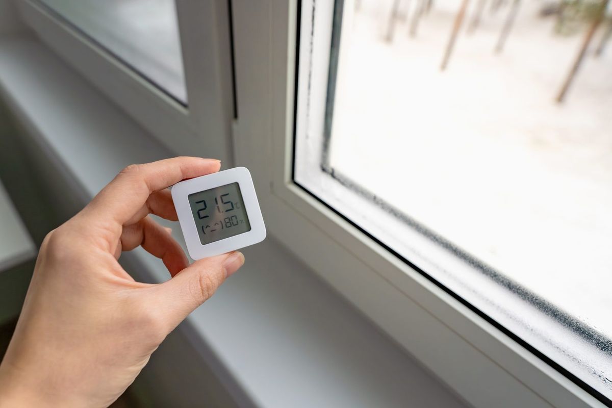 Hygromètre indiquant un taux d'humidité élevé près d'une fenêtre embuée