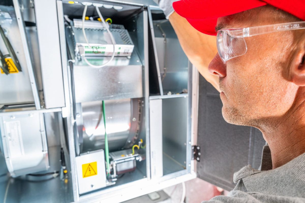 Technicien contrôlant un caisson de VMC double flux ouvert